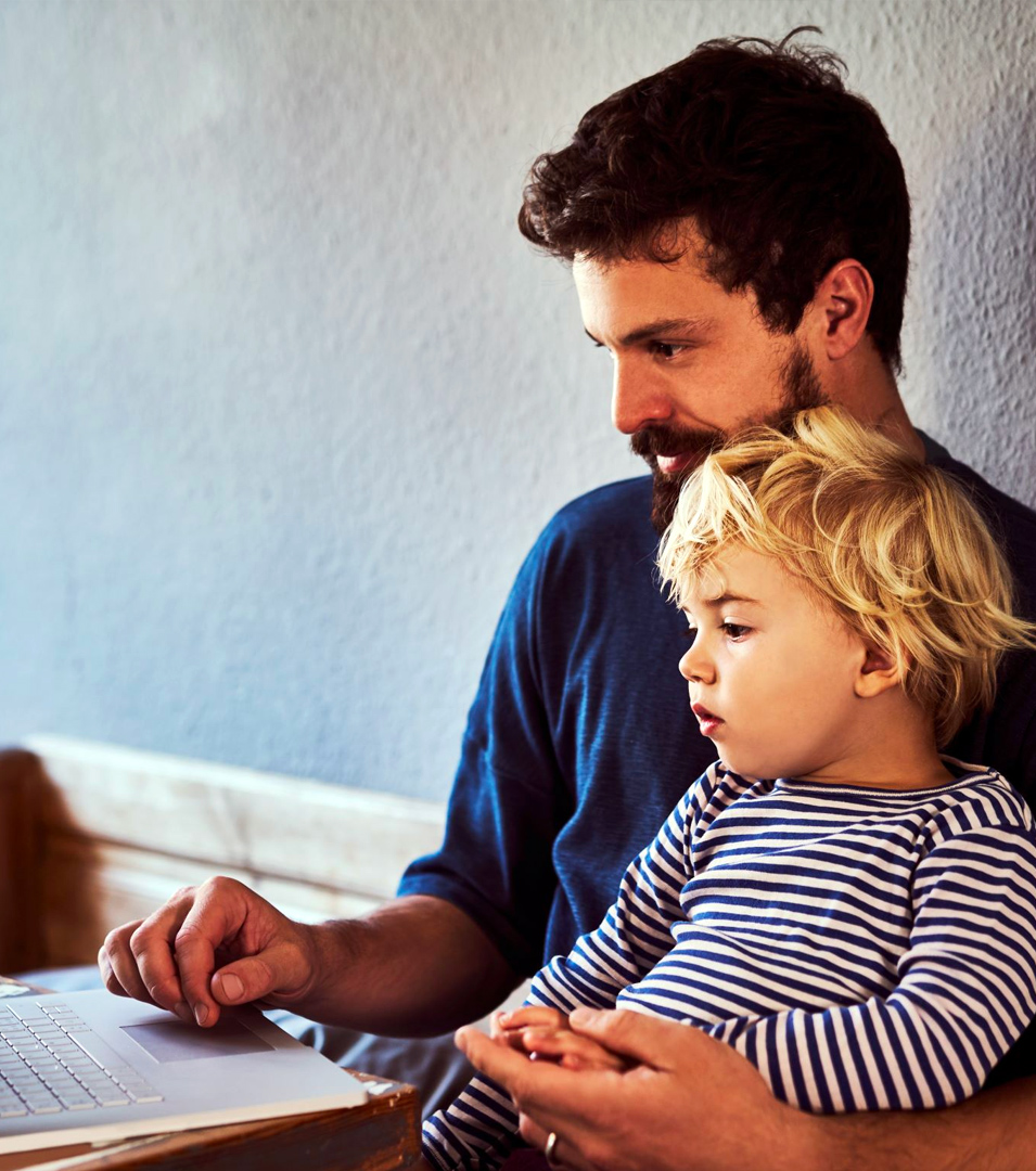 Man with child reviewing benefits at home on laptop computer 