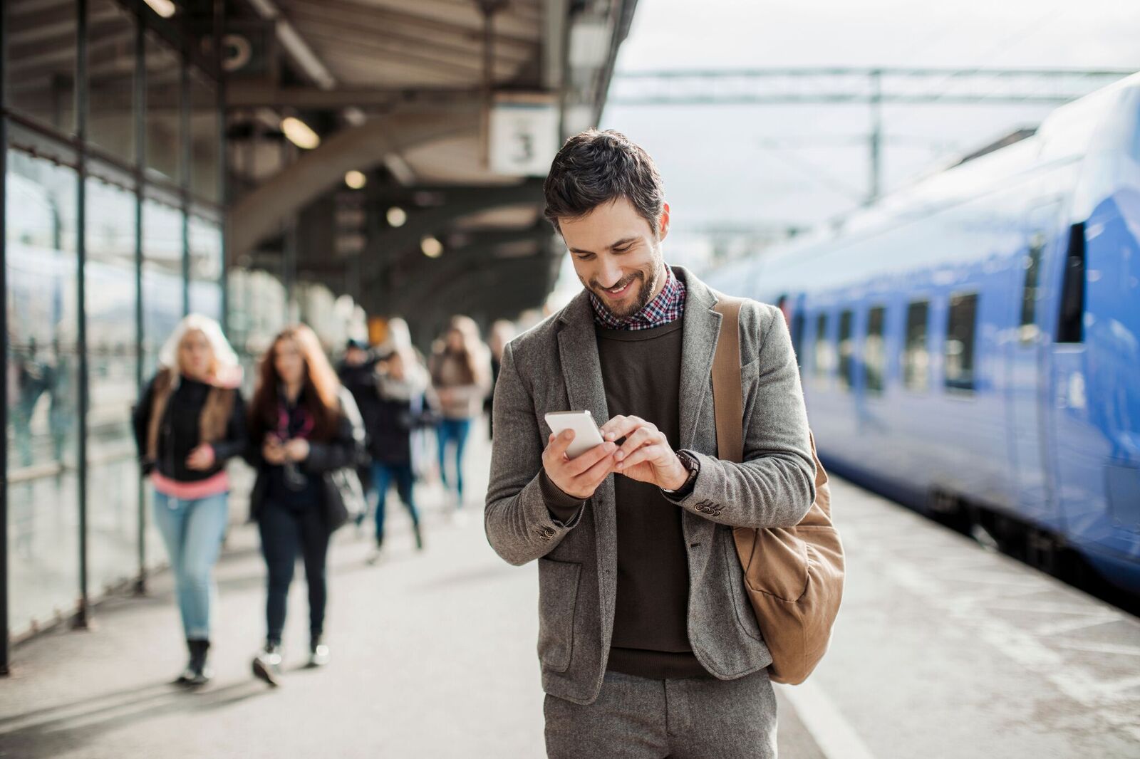 Man at Train Station Smiling Looking At Phone